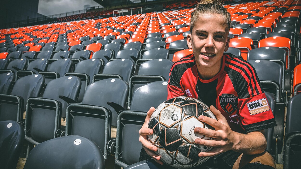 Antoine Coupland, assis dans les gradins d'un stade, tient un ballon de soccer dans ses mains. Antoine Coupland, assis dans les gradins d'un stade, tient un ballon de soccer dans ses mains.