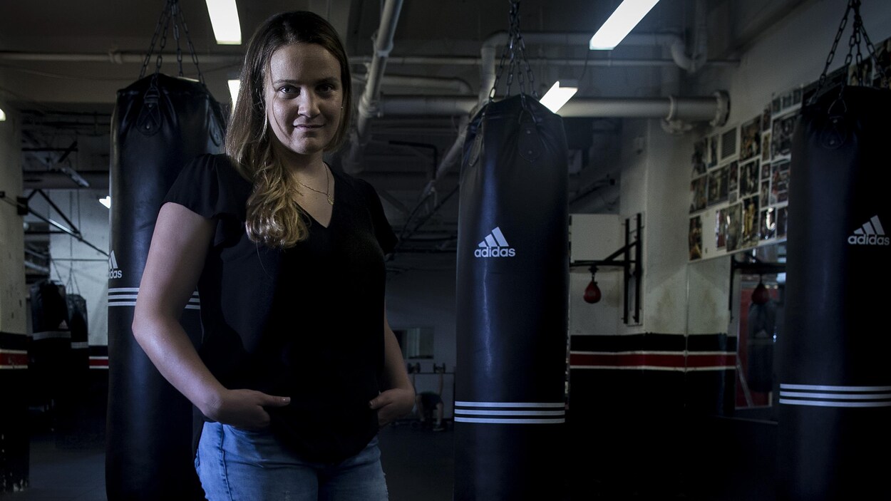 Elle pose devant des sacs dans un gymnase.