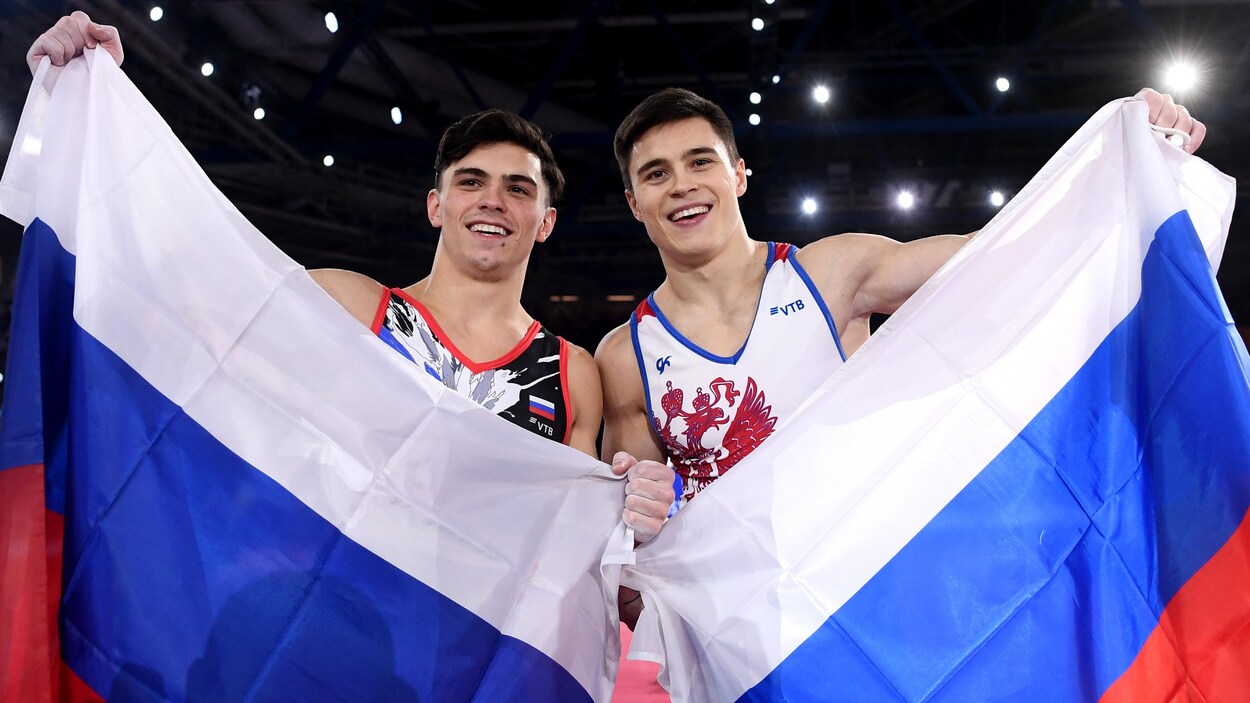 Doublé russe au concours général individuel des Championnats du monde de gymnastique à Stuttgart: (à gauche) Artur Dalaloyan (argent) et Nikita Nagorniy (or) brandissent chacun un drapeau russe.