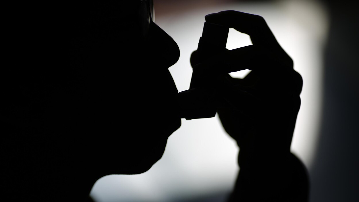 Une personne asthmatique, de profil, utilise sa pompe. Une personne asthmatique, de profil, utilise sa pompe.