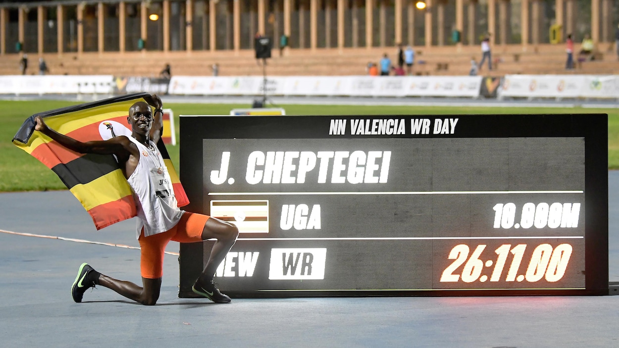 Il est à genoux devant un tableau électronique en bordure de la piste.
