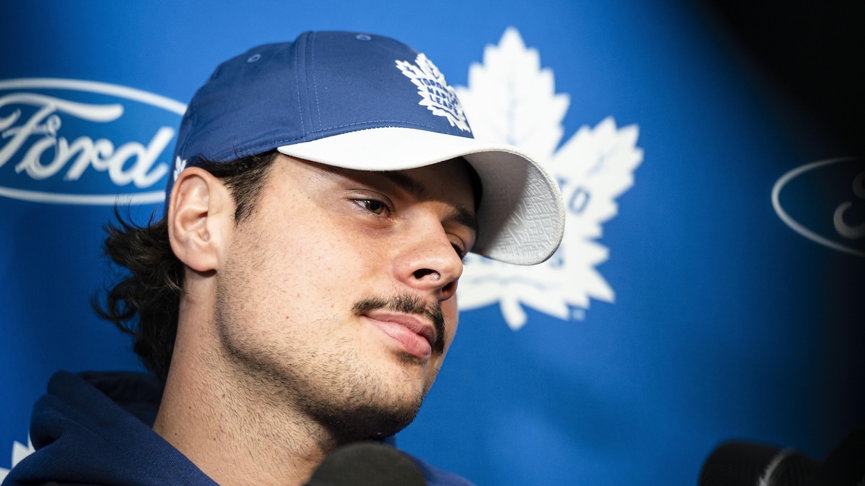 Un joueur avec une casquette participe à une mêlée de presse.