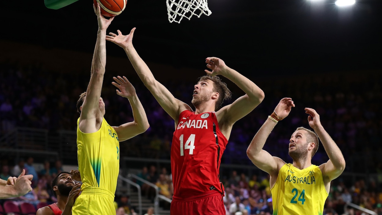 Erik Nissen (au centre), du Canada, tente d'empêcher son adversaire australien de marquer. Erik Nissen (au centre), du Canada, tente d'empêcher son adversaire australien de marquer.