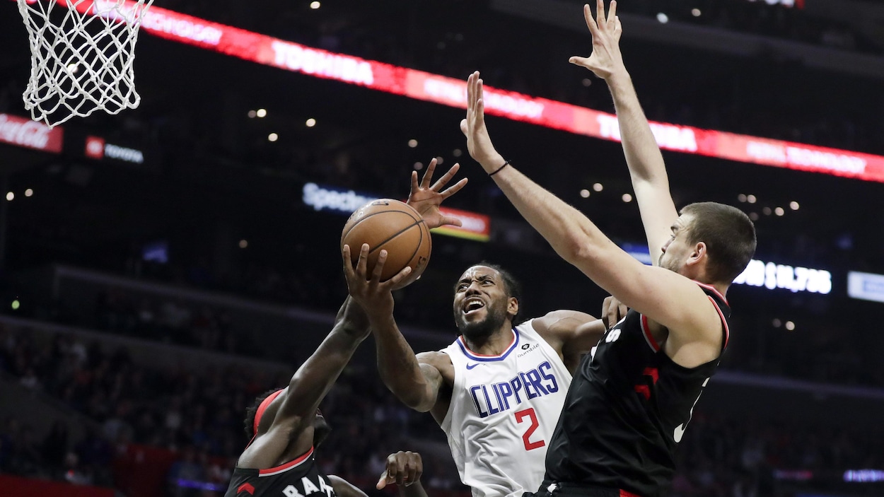 Leonard se faufile entre les deux joueurs des Raptors de Toronto.