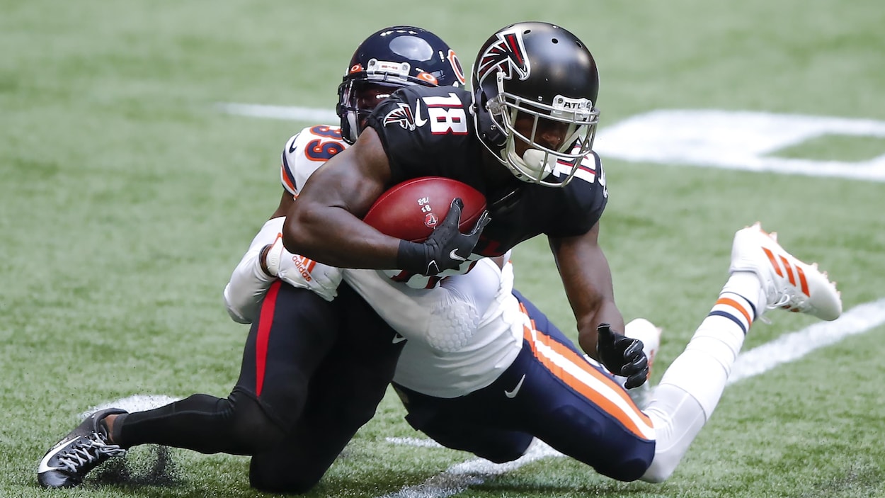 Deux joueurs de football tombent au sol.