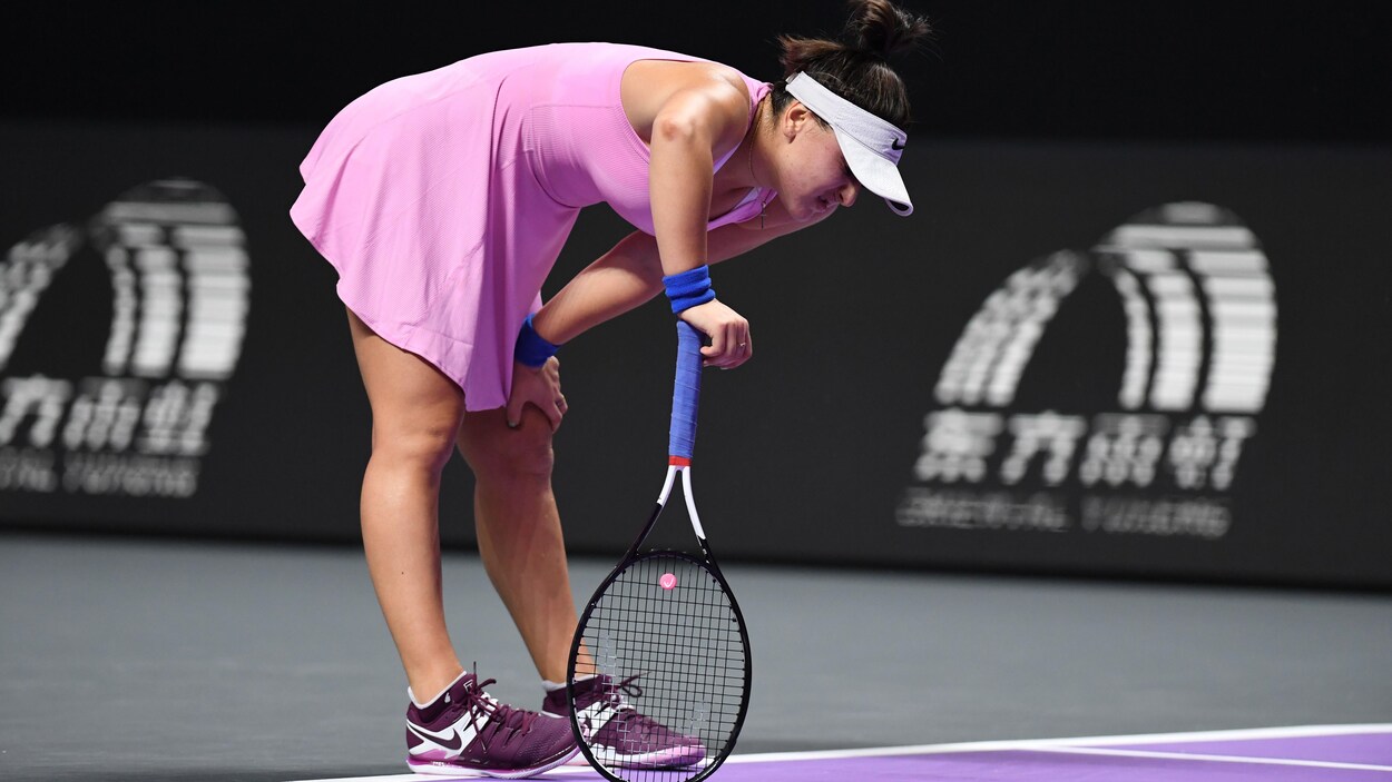 Une joueuse de tennis s'accroupit pour reprendre son souffle après un échange.