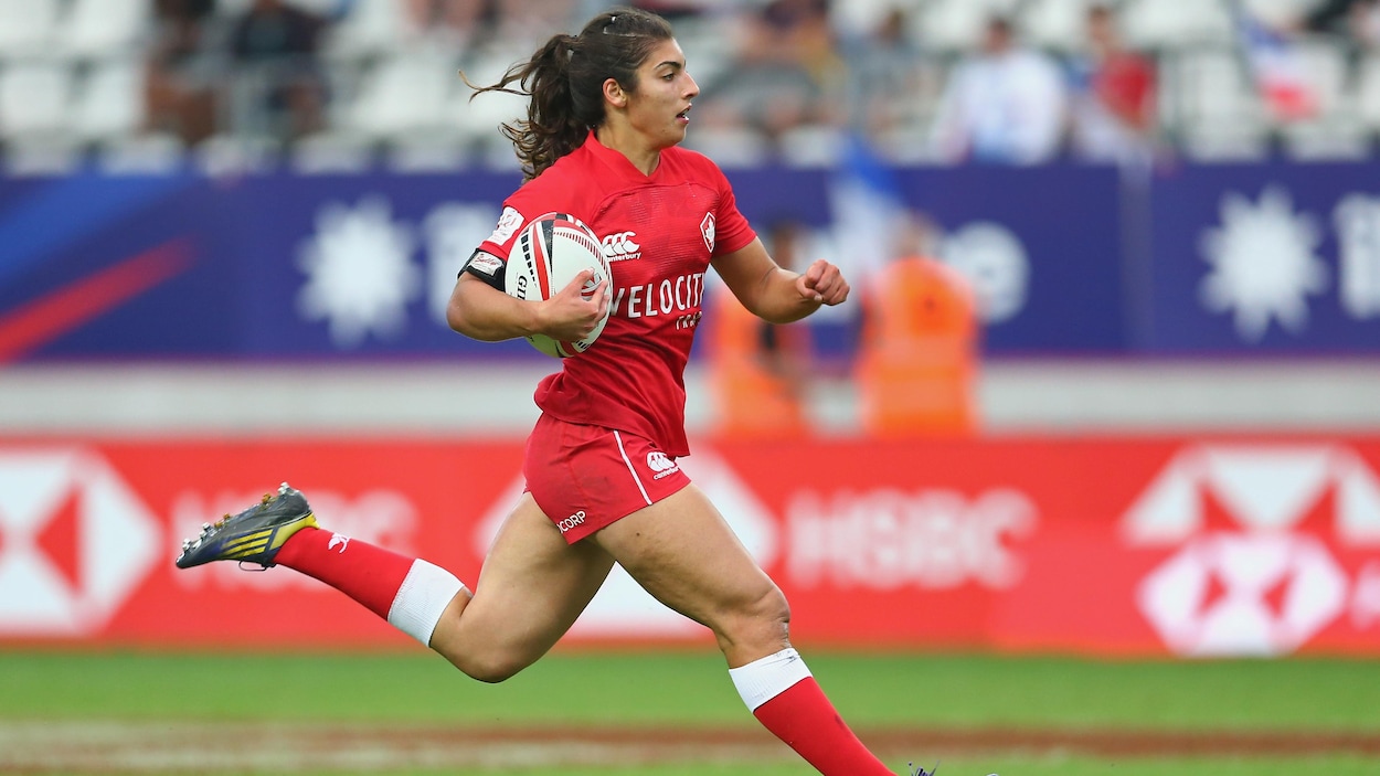 Elle court avec le ballon dans sa main droite.