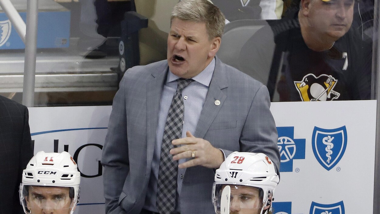 Un entraîneur donne des directives à ses joueurs sur la glace.