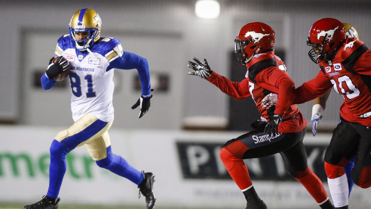 Deux joueurs des Stampeders tentent d'atteindre Chris Givens des Blue Bombers qui court avec le ballon. Deux joueurs des Stampeders tentent d'atteindre Chris Givens des Blue Bombers qui court avec le ballon.