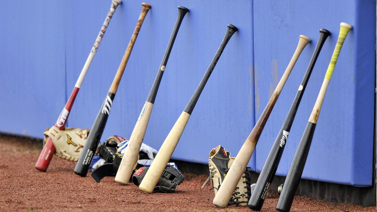 Des bâtons et des gants de baseball posés sur le sol.