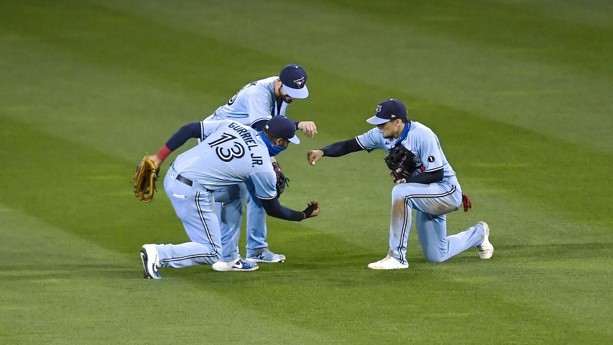 Trois coéquipiers célèbrent ensemble sur un terrain de baseball.