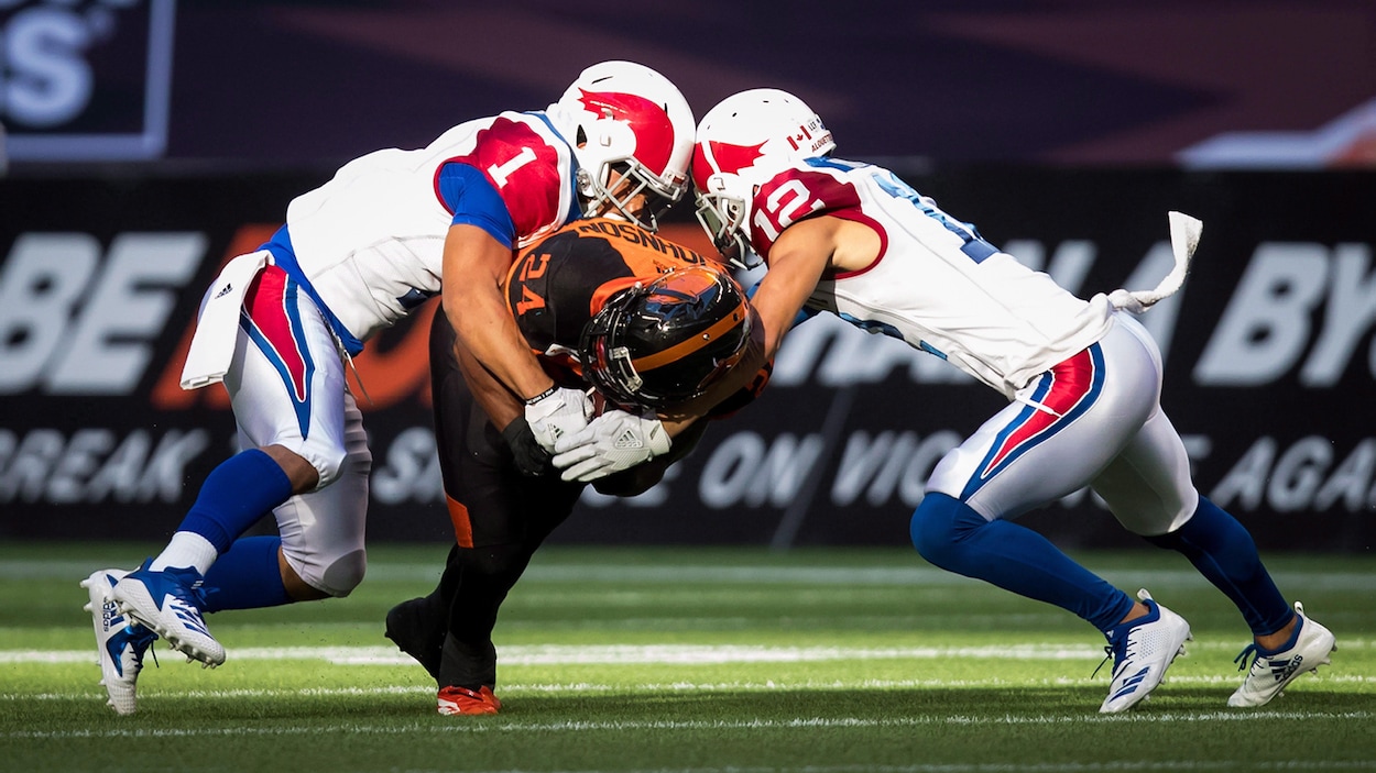 Branden Dozier (à gauche) et Mitchell White tentent de plaquer le joueur des Lions Jeremiah Johnson.