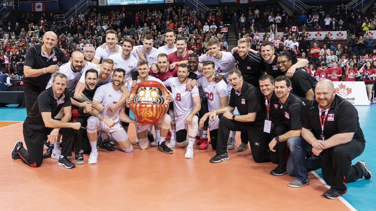 Il pose en demi-cercle avec leur trophée.