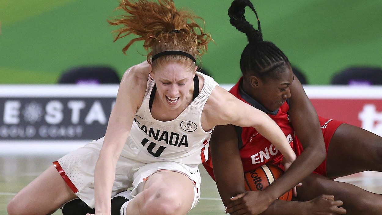 Deux joueuses de basketball sont au sol et luttent pour le ballon.