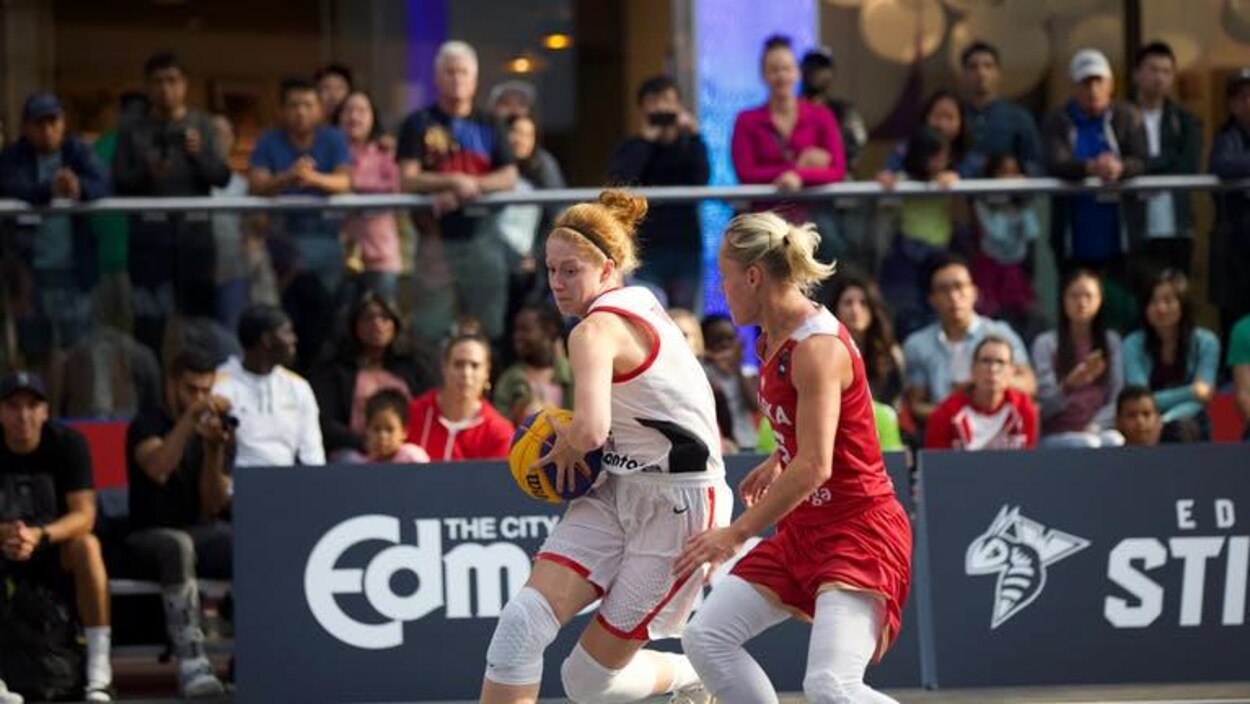 Une joueuse de basketball protège son ballon contre une adversaire.