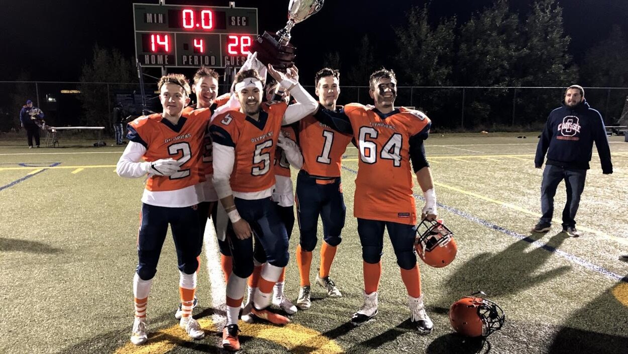 Cinq joueurs de football tiennent une coupe au-dessus de leur tête.