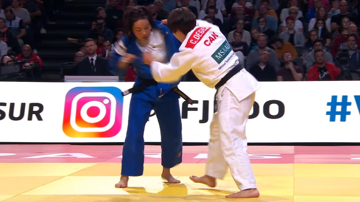 Elle attrape le judogi de son adversaire.