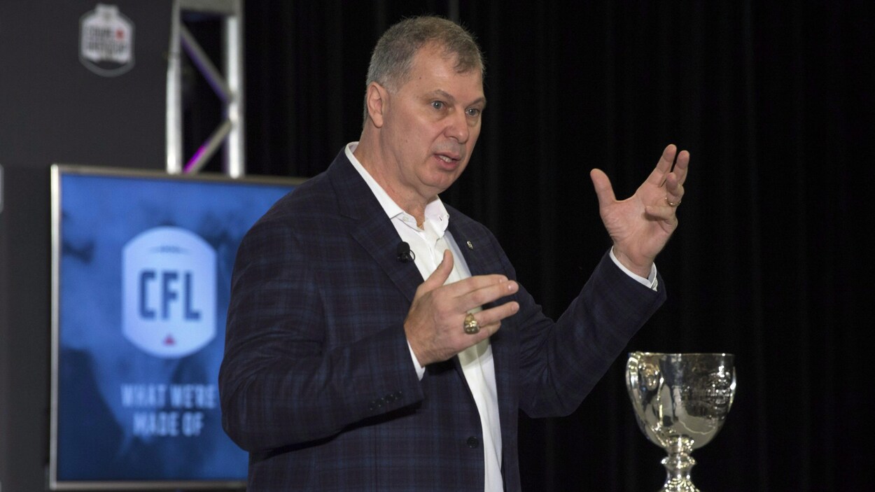 Randy Ambrosie est debout sur une scène, devant la coupe Grey. Randy Ambrosie est debout sur une scène, devant la coupe Grey.
