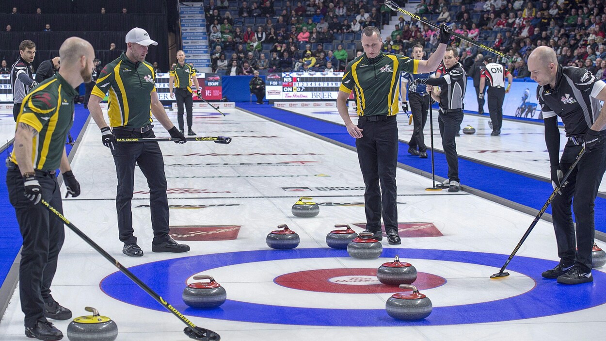 Ryan Fry, Ryan Harnden et E.J. Harnden, réagissent à la suite du lancer du capitaine Brad Jacobs, qui a permis à l'équipe du Nord de l'Ontario d'inscrire six points dès la première manche d'un duel face à l'équipe de Mike McEwen