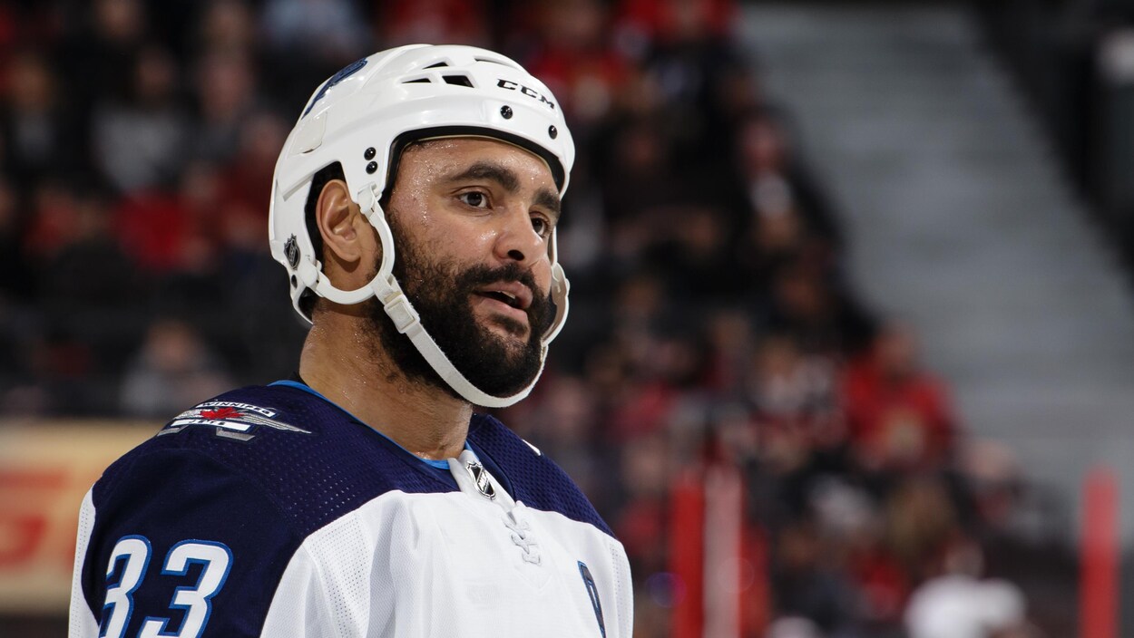 L'air songeur, il porte un casque de hockey blanc.