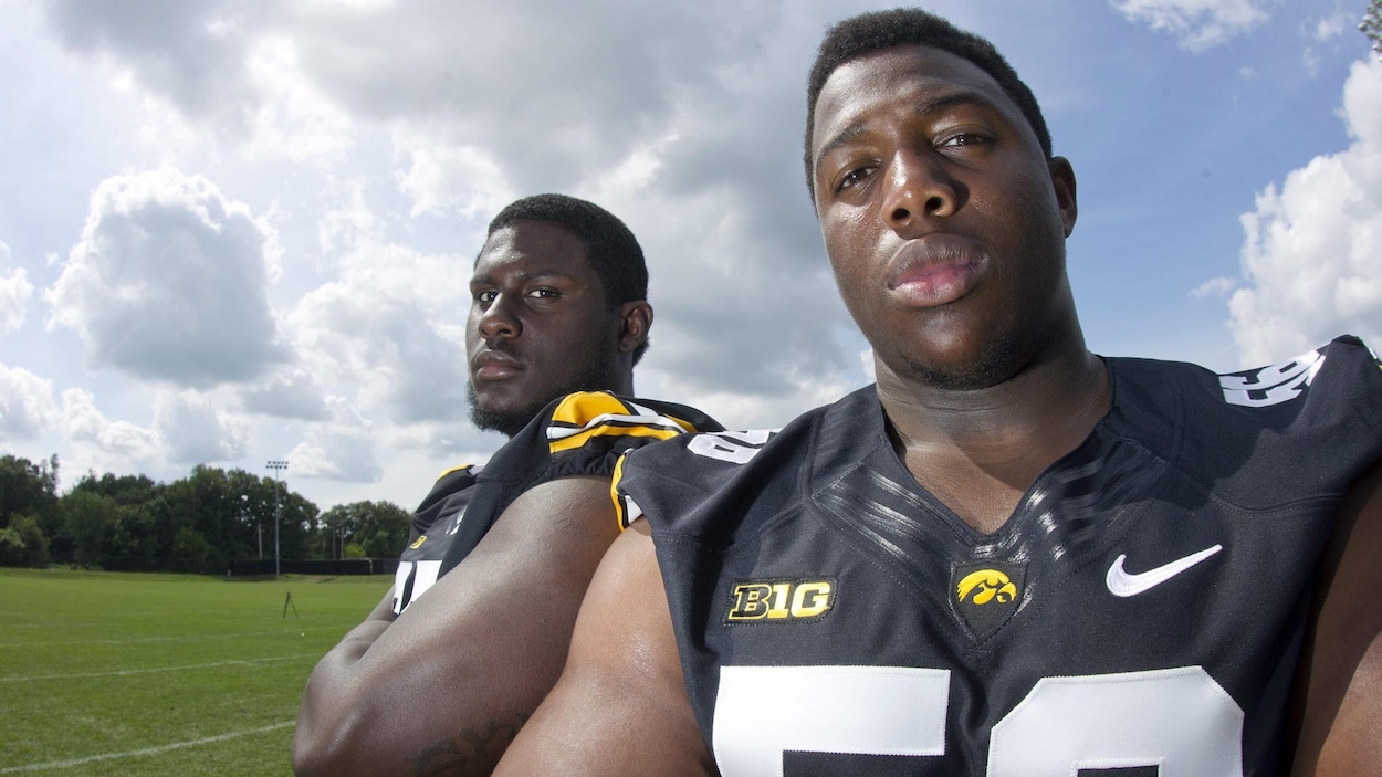 Le joueur de ligne défensive Faith Ekakitie (devant) les bras croisés avec un chandail noir des Hawkeyes de l'Université de l'Iowa. Le joueur de ligne défensive Faith Ekakitie (devant) les bras croisés avec un chandail noir des Hawkeyes de l'Université de l'Iowa.
