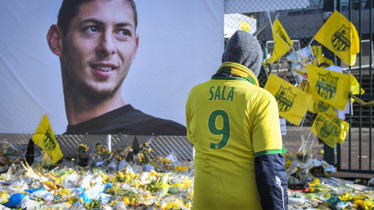 Un homme rend hommage à un joueur de soccer disparu, en portant son chandail.
