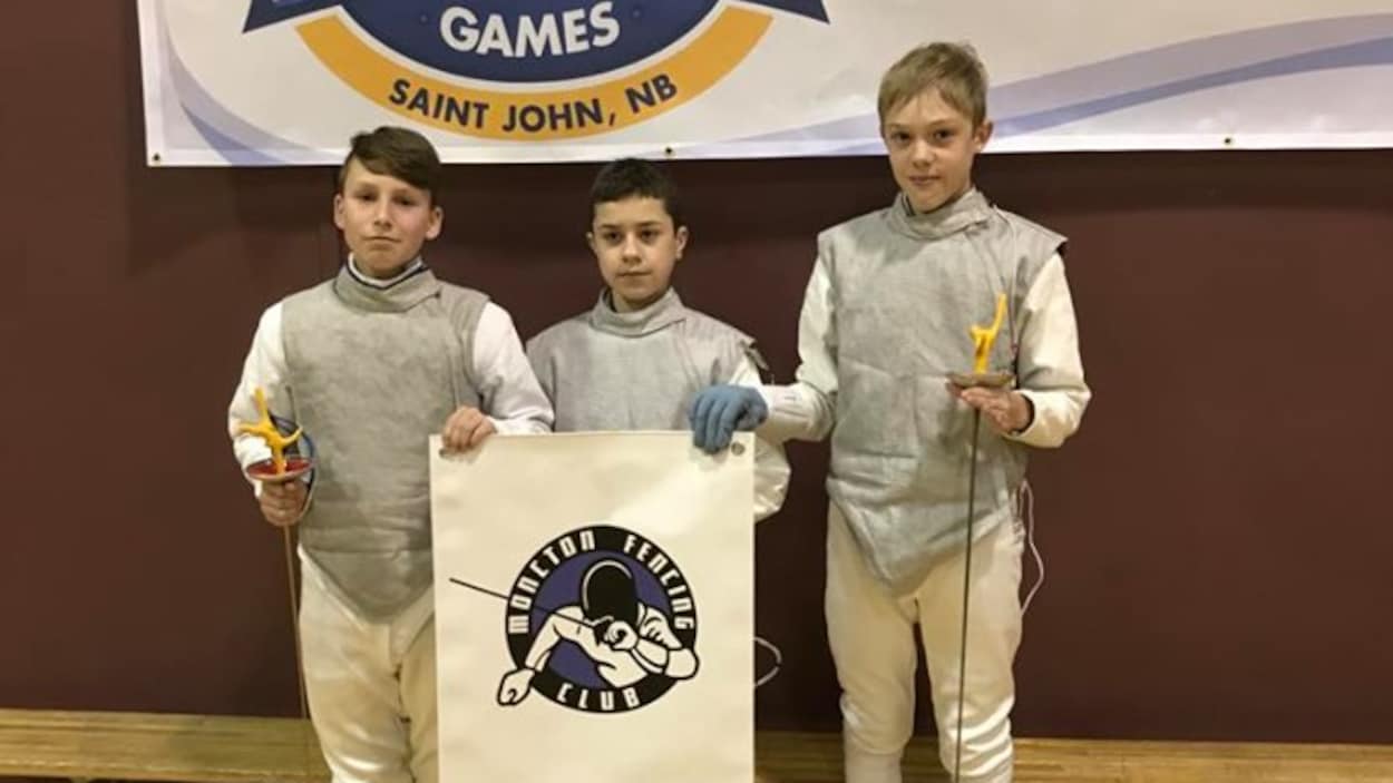 De gauche à droite: Anthony Gauvin, Mason Perley et Michael Robichaud, tenant la bannière du Club d'escrime de Moncton.