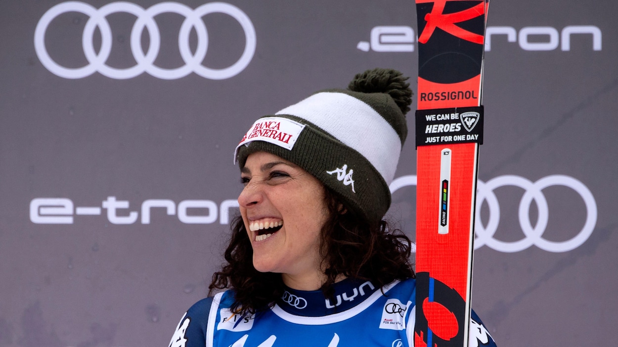 Ses skis en main, elle sourit sur le podium.