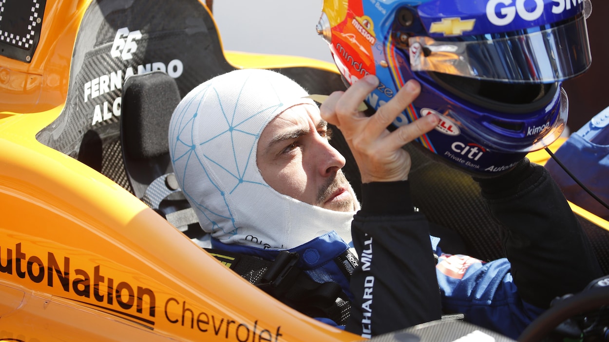 Assis dans sa voiture, il met son casque.