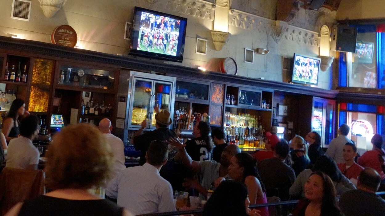 Des partisans de football regardent un match dans un bar.