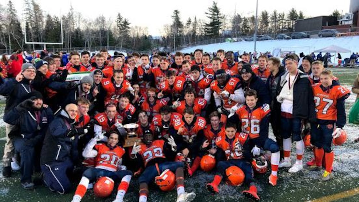 Joueurs et entraîneurs regroupés autour du trophée.