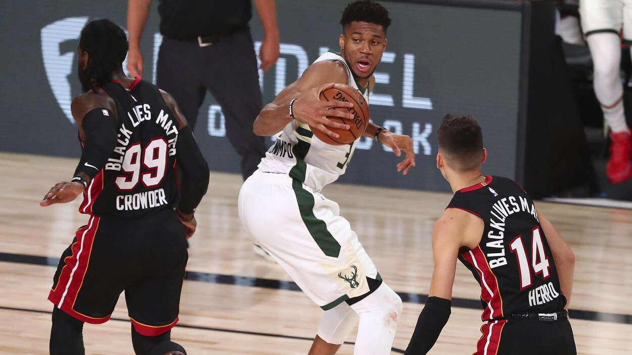 Il tient le ballon de la main droite et tente de déjouer deux joueurs du Heat, Jae Crowder (no 99) et Tyler Herro (no 14).