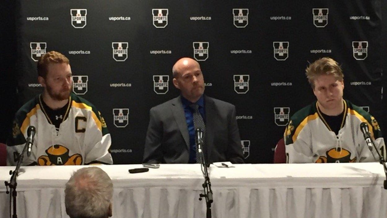 Le capitaine des Golden Bears de l'Université de l'Alberta, Brennan Yadlowski, l'entraîneur-chef Serge Lajoie et l'attaquant Jamie Crooks s'adressent aux médias à la suite de la défaite subie aux mains des Axemen d'Acadia. Le capitaine des Golden Bears de l'Université de l'Alberta, Brennan Yadlowski, l'entraîneur-chef Serge Lajoie et l'attaquant Jamie Crooks s'adressent aux médias à la suite de la défaite subie aux mains des Axemen d'Acadia.