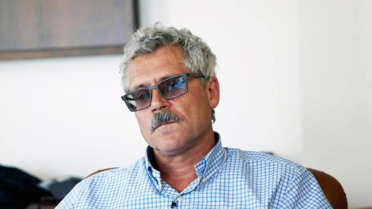 Un homme, l'air sombre, en entrevue
