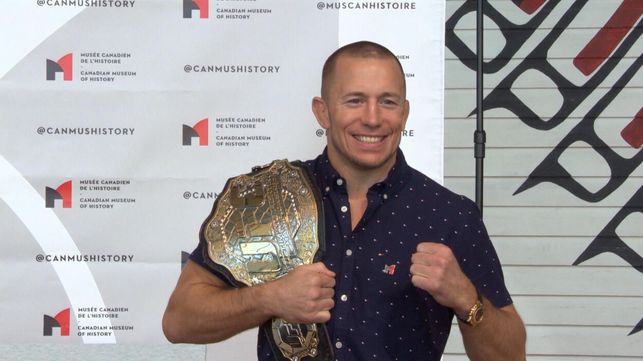 Georges St-Pierre montre fièrement sa ceinture avec un poing levé