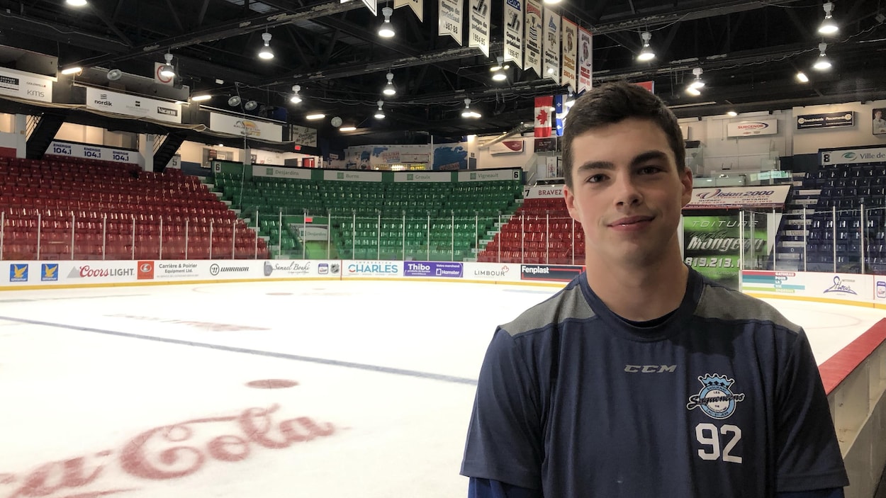Un joueur de hockey prend la pose pour la caméra près de la glace d'un aréna