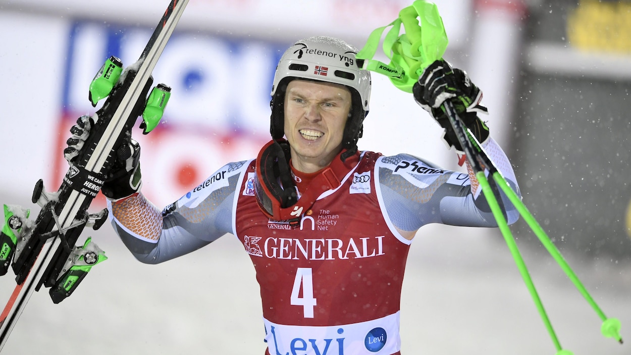 Il lève les bras en célébration de sa victoire.