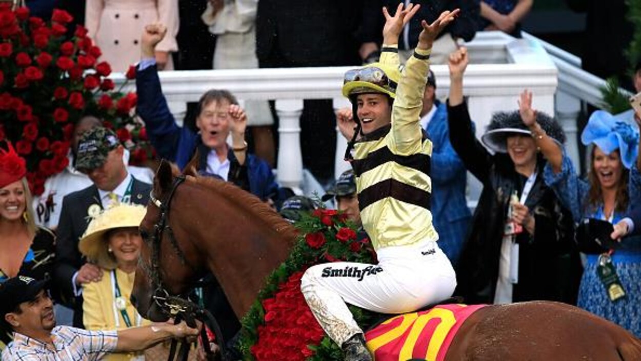 Le jockey, bien en selle, lève les bras dans le cercle du vainqueur.
