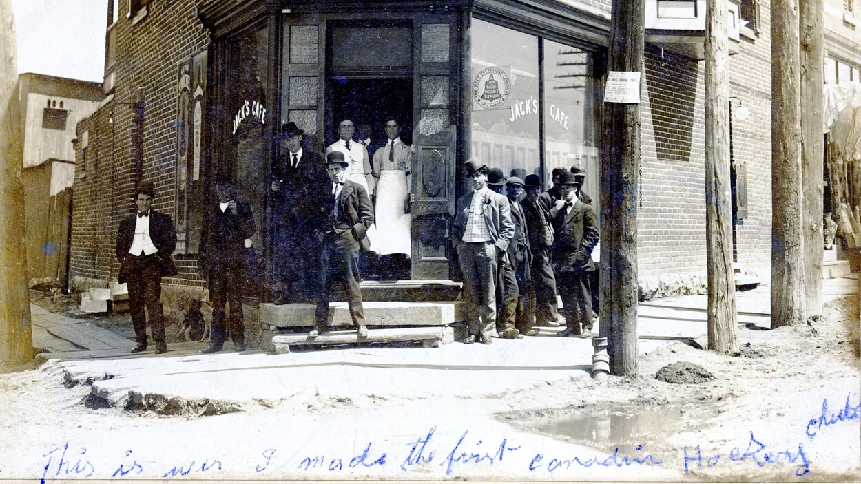 Des hommes prennent la pose devant la façade du commerce.