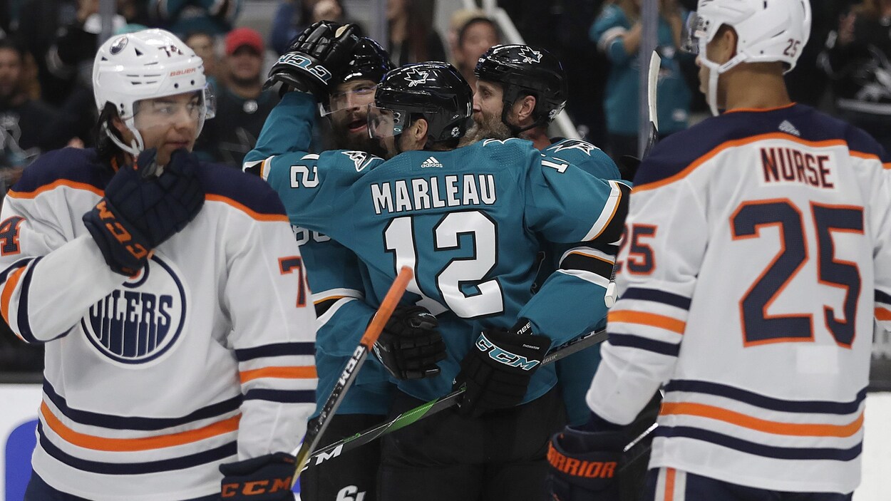 Les trois joueurs des Sharks s'enlacent.