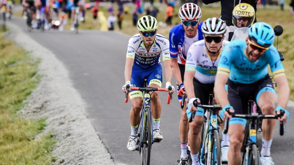 Il grimace sous l'effort, à l'avant d'un groupe de cyclistes.