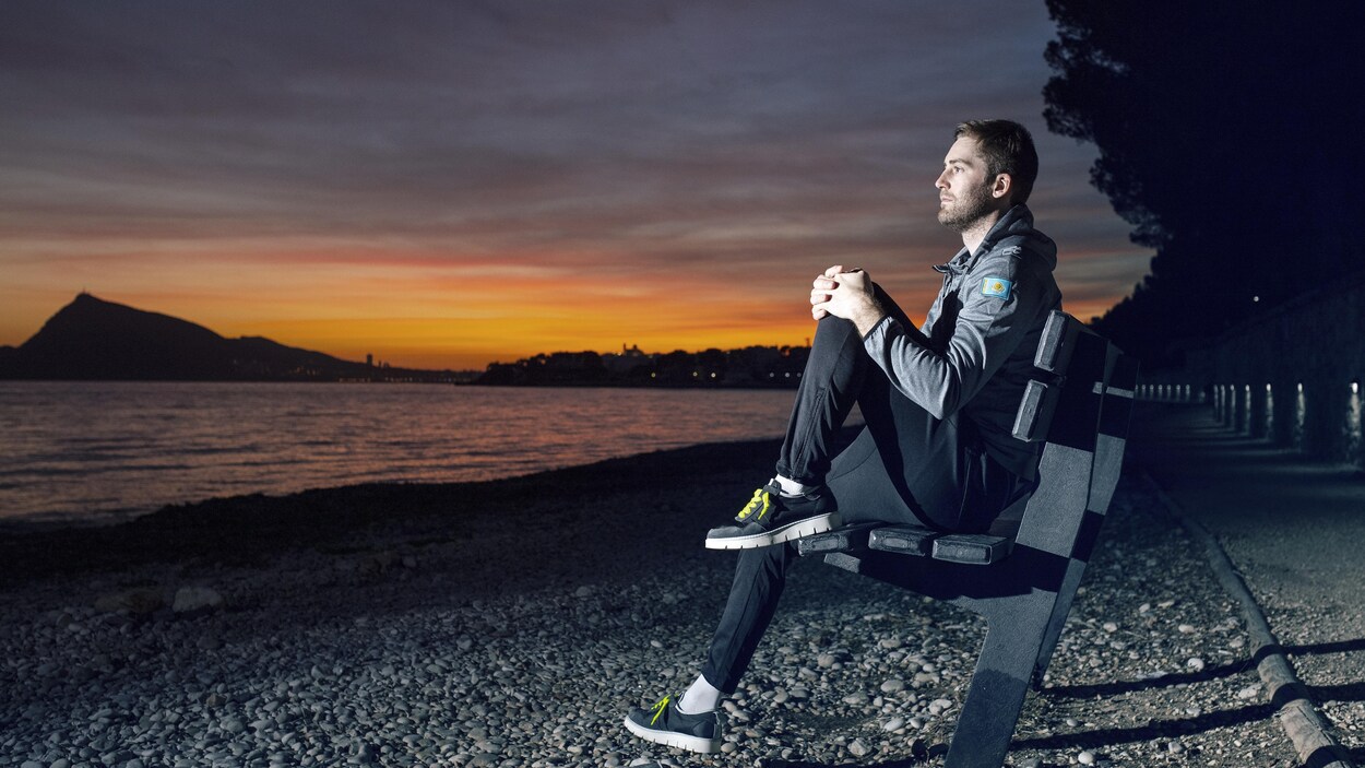 Hugo Houle est assis sur un banc devant un lac. Hugo Houle est assis sur un banc devant un lac.