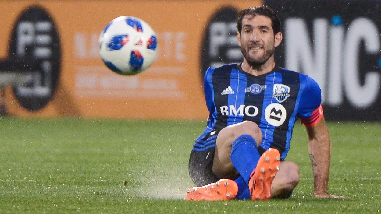 Il est assis sur le terrain et regarde le ballon devant lui.