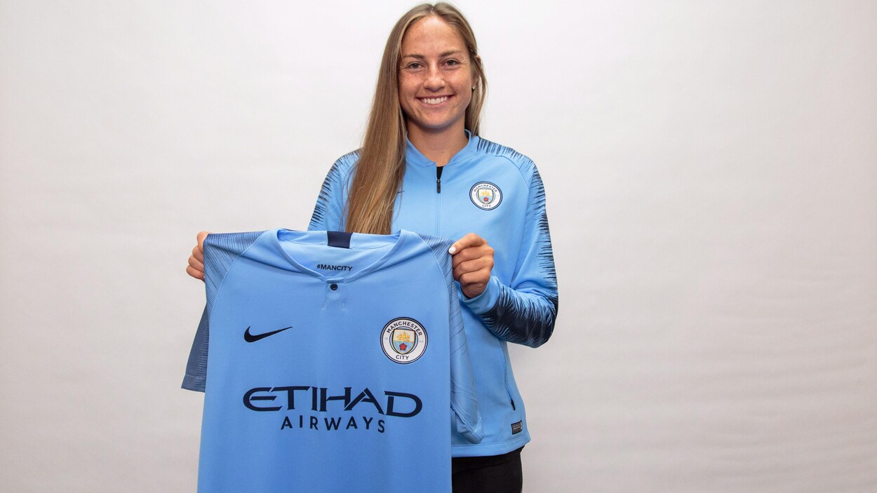 Janine Beckie tout sourire, avec son chandail de Manchester City Janine Beckie tout sourire, avec son chandail de Manchester City