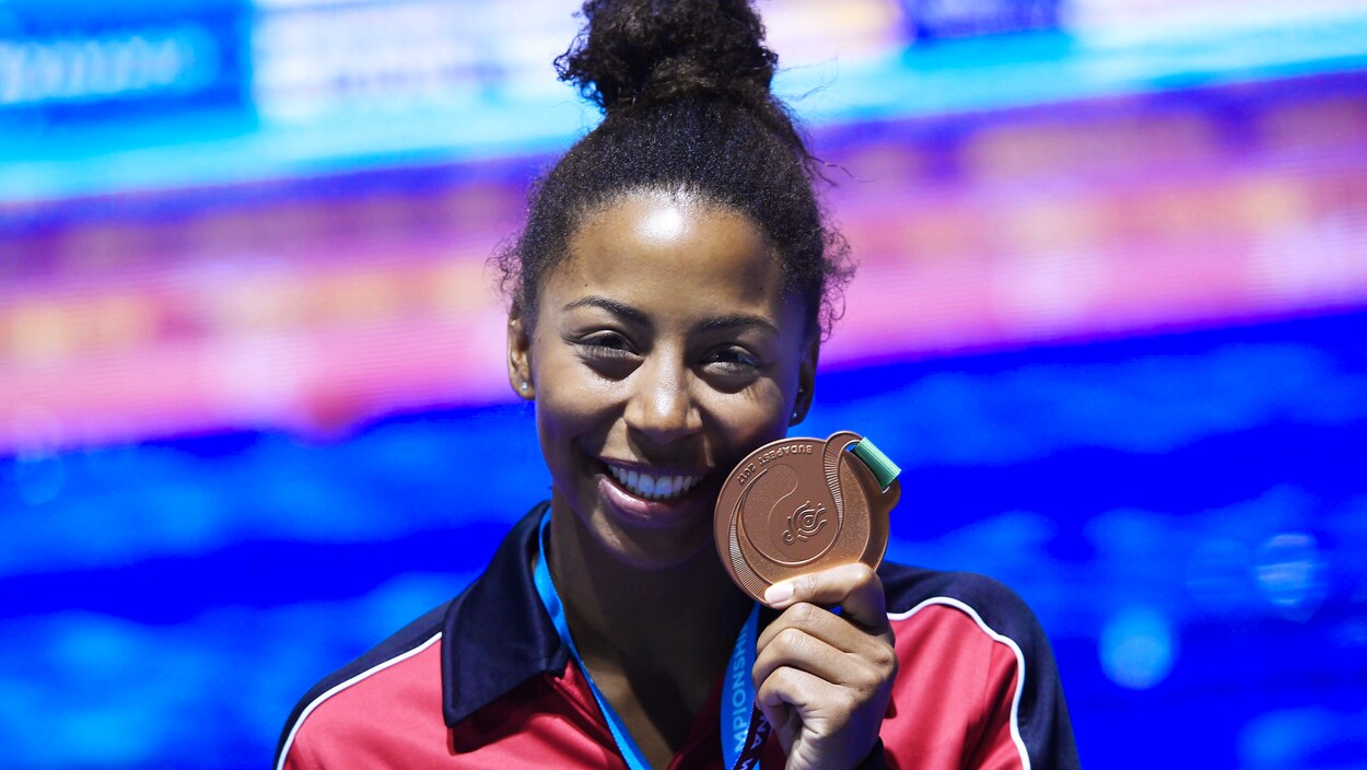 Jennifer Abel tient sa médaille en souriant. Jennifer Abel tient sa médaille en souriant.