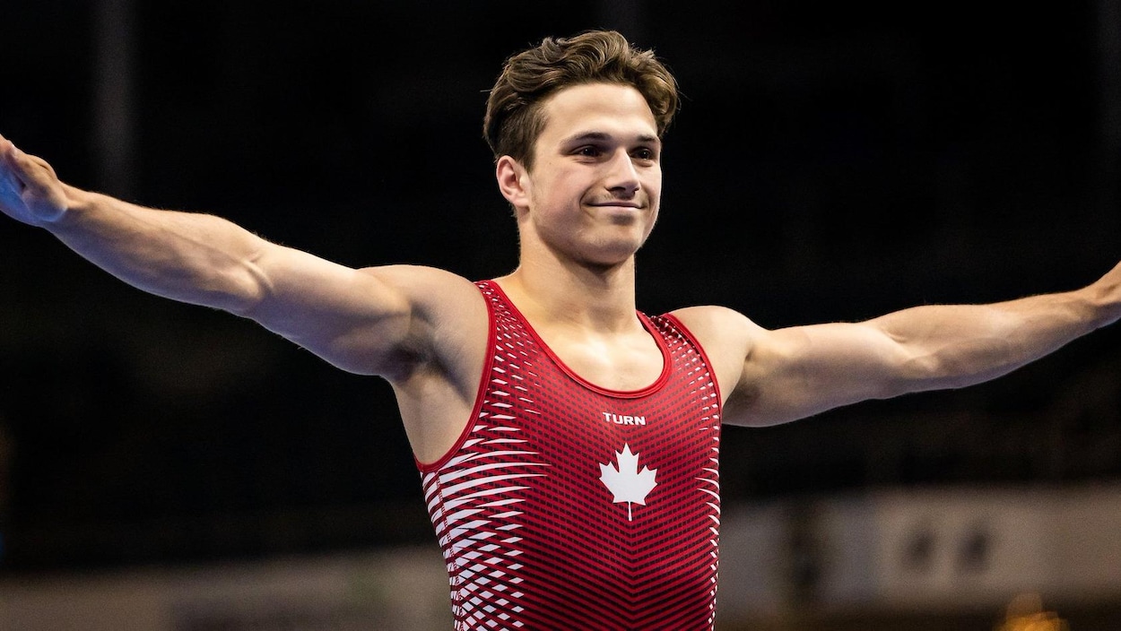 Le trampoliniste canadien Jérémy Chartier, les bras en croix, souriant à la foule après une épreuve.