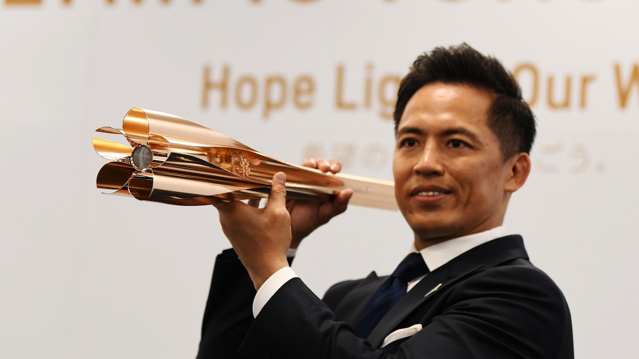 Tadahiro Nomura, triple champion olympique japonais de judo, présente le flambeau olympique des Jeux de Toyko.