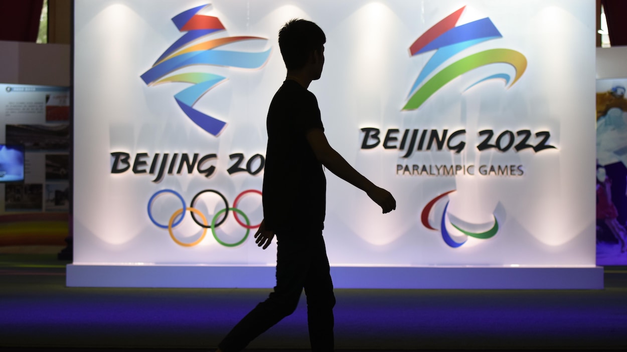 Un homme marche devant le logo des Jeux olympiques et paralympiques de Pékin. Un homme marche devant le logo des Jeux olympiques et paralympiques de Pékin.
