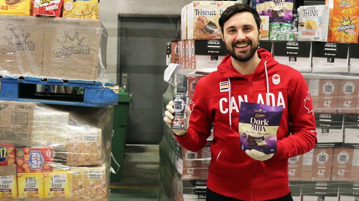 Dans un entrepôt, un homme tient des provisions dans ses mains.