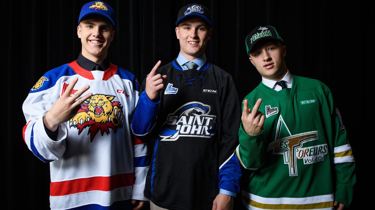 Trois joueurs de hockey font signe de la main pour montrer leur rang de sélection